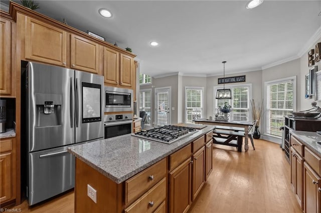 6089 Pleasant Field Dr, Greensboro, NC 27455 - kitchen with stainless steel appliances, a kitchen island, ornamental molding, light stone counters, and light wood-style flooring