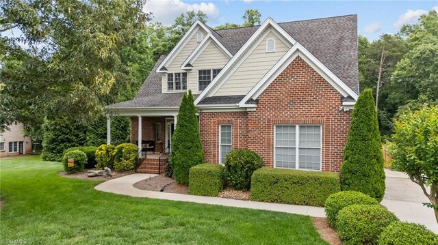 6089 Pleasant Field Dr, Greensboro, NC 27455 - traditional home featuring a front lawn, covered porch, brick siding, and a shingled roof
