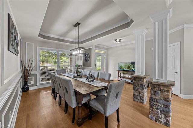 6089 Pleasant Field Dr, Greensboro, NC 27455 - dining area featuring decorative columns, a tray ceiling, light wood-type flooring, ornamental molding, and a decorative wall