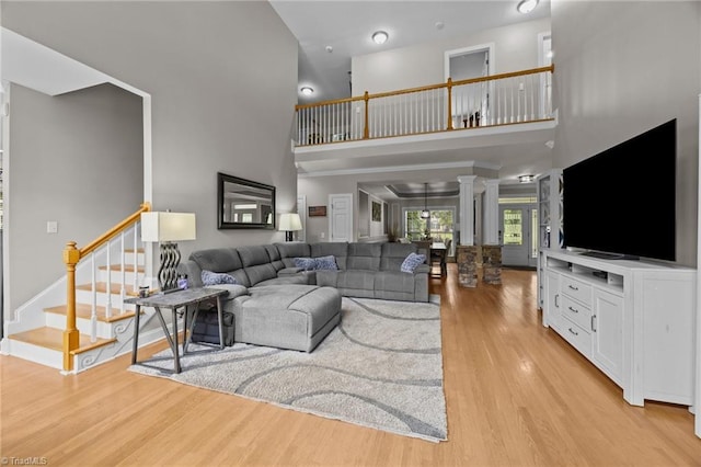 6089 Pleasant Field Dr, Greensboro, NC 27455 - living room featuring a high ceiling, light wood-style floors, decorative columns, and stairway