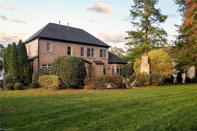 back house at dusk with a lawn