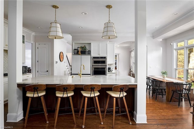 kitchen with sink, backsplash, double oven, kitchen peninsula, and dark hardwood / wood-style flooring