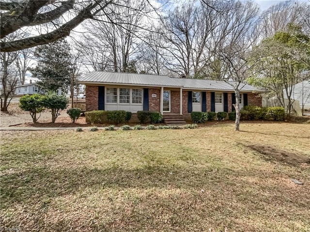 single story home featuring metal roof, brick siding, and a front yard