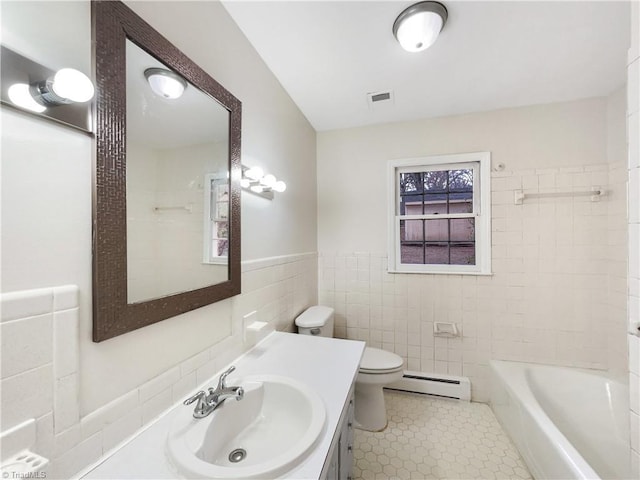 bathroom with toilet, a baseboard heating unit, vanity, visible vents, and tile walls