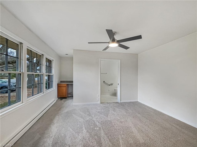 spare room with a baseboard heating unit, light carpet, baseboards, and a ceiling fan