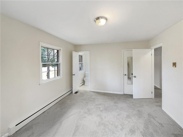 spare room with a baseboard heating unit, carpet, and baseboards