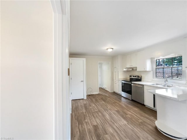 kitchen featuring under cabinet range hood, a sink, white cabinetry, light countertops, and appliances with stainless steel finishes