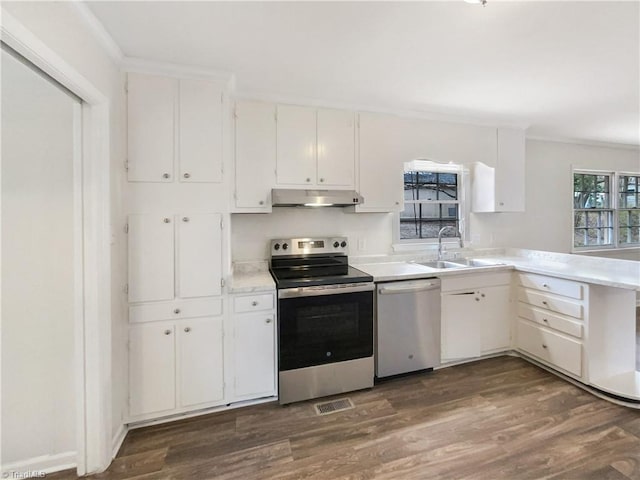 kitchen with dark wood finished floors, appliances with stainless steel finishes, light countertops, under cabinet range hood, and a sink