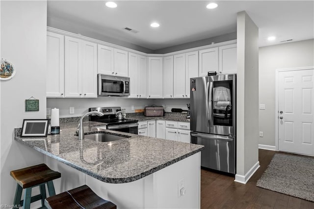 211 Hawks Nest Cir, Clemmons, NC 27012 - kitchen featuring appliances with stainless steel finishes, a peninsula, dark wood-style flooring, white cabinets, and recessed lighting