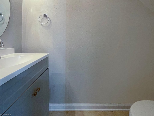 half bathroom featuring vanity, baseboards, and tile patterned floors