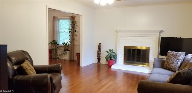 living room with crown molding, a fireplace, ceiling fan, and dark hardwood / wood-style floors