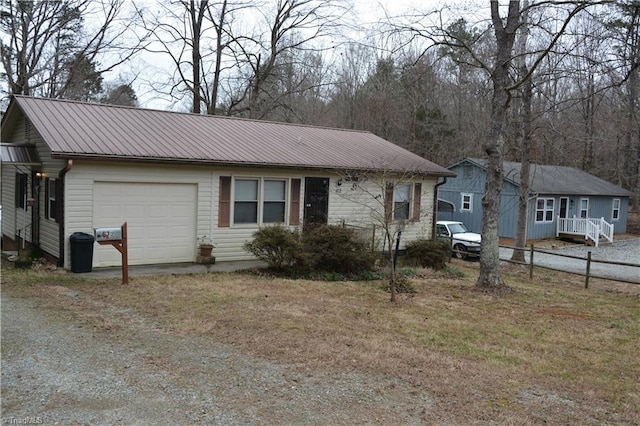 view of front of home featuring dirt driveway, metal roof, an attached garage, and fence