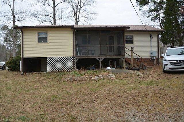 rear view of property with a yard, a sunroom, and metal roof