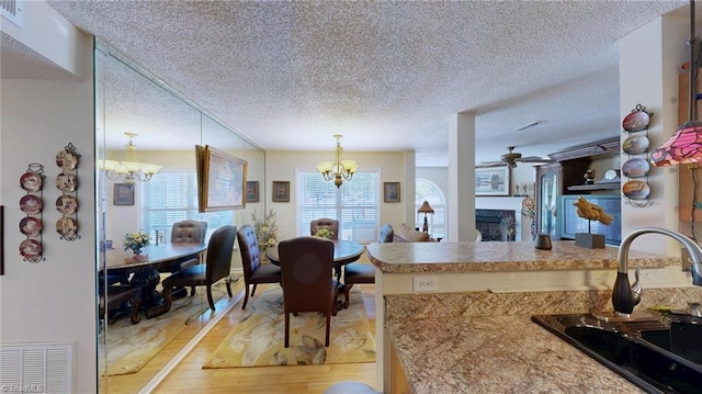 kitchen with a chandelier, a sink, a textured ceiling, light wood-style flooring, and ceiling fan