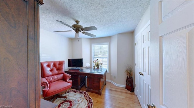 home office featuring light wood-style flooring, ceiling fan, a textured ceiling, and baseboards