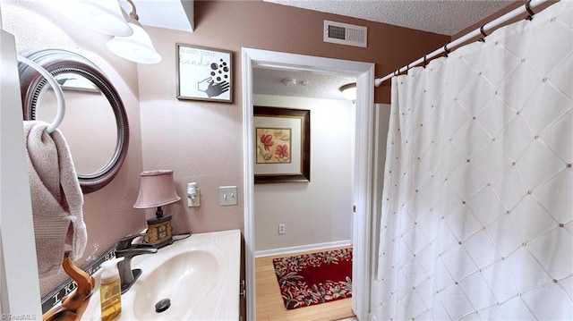 bathroom featuring a textured ceiling, vanity, a shower with curtain, and baseboards