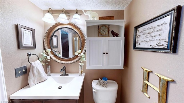 half bath featuring toilet, vanity, and a textured ceiling