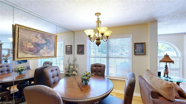 dining room featuring a chandelier, a textured ceiling, and wood finished floors