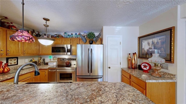 kitchen featuring appliances with stainless steel finishes, a sink, brown cabinetry, and a textured ceiling
