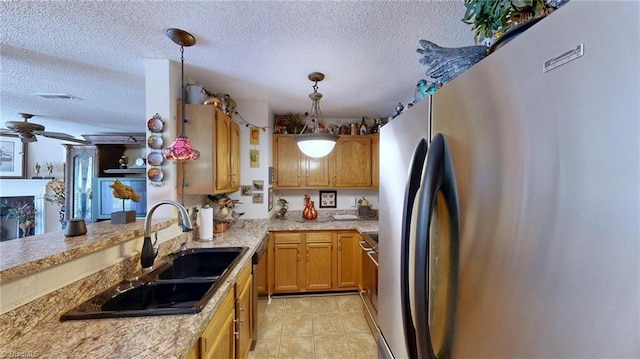 kitchen with appliances with stainless steel finishes, a sink, a textured ceiling, pendant lighting, and light tile patterned floors