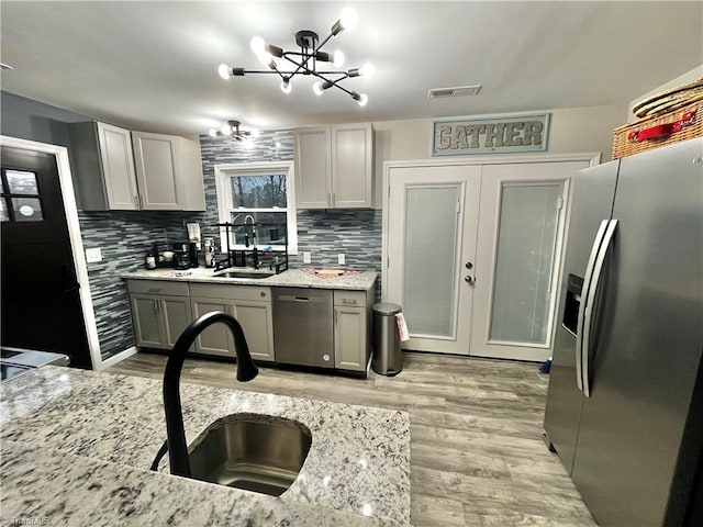 kitchen featuring gray cabinetry, sink, appliances with stainless steel finishes, and an inviting chandelier