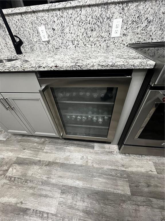 room details with light stone countertops, beverage cooler, and sink