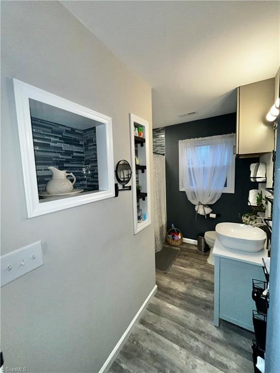 bathroom featuring wood-type flooring, vanity, and toilet