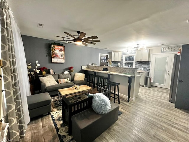 living room with ceiling fan and light hardwood / wood-style flooring