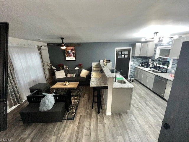 kitchen featuring white cabinetry, sink, stainless steel dishwasher, a kitchen bar, and decorative backsplash