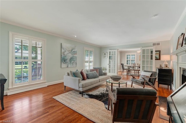living area with crown molding, french doors, wood finished floors, and visible vents
