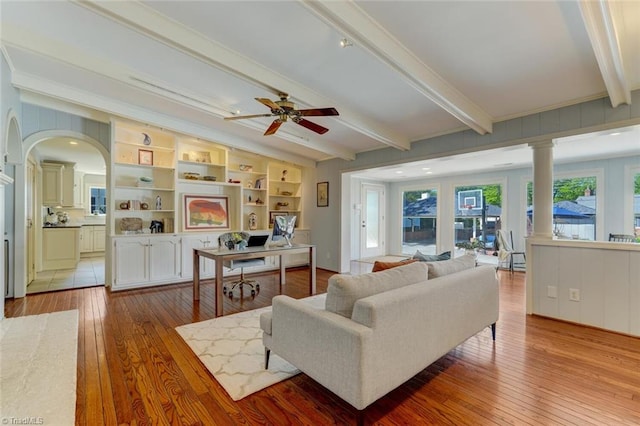 living room featuring arched walkways, ceiling fan, beam ceiling, and hardwood / wood-style floors