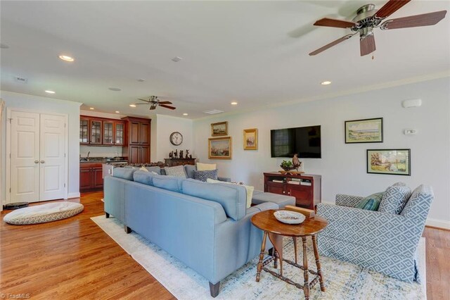 living room with crown molding, recessed lighting, ceiling fan, and light wood-type flooring
