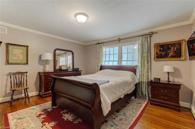 bedroom with crown molding, baseboards, visible vents, and wood finished floors