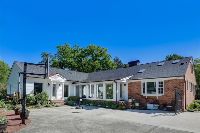 single story home with brick siding, a shingled roof, and a chimney