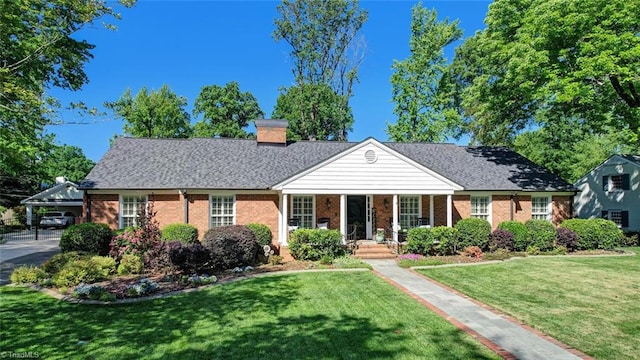 view of front of property featuring a porch, a chimney, a front yard, and brick siding