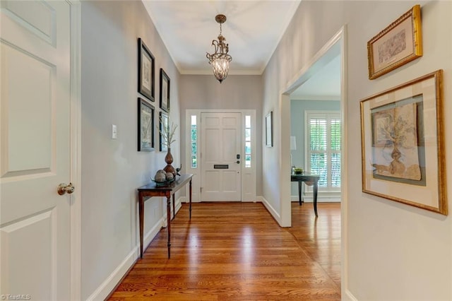 foyer featuring crown molding, baseboards, light wood finished floors, and a notable chandelier