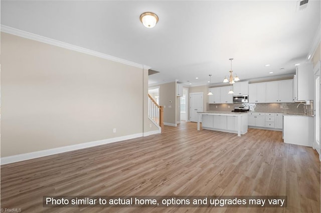 unfurnished living room with stairway, baseboards, ornamental molding, and a sink