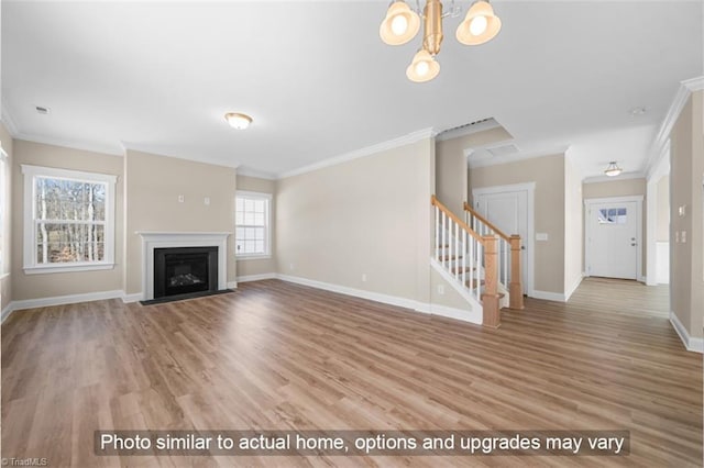 unfurnished living room with a fireplace with flush hearth, ornamental molding, wood finished floors, baseboards, and stairs