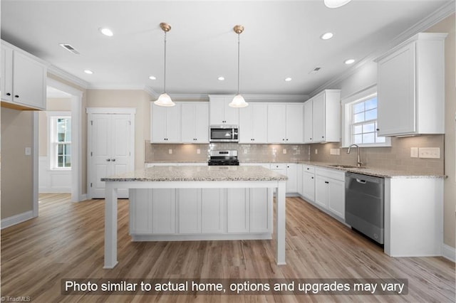 kitchen with a sink, appliances with stainless steel finishes, white cabinets, and crown molding