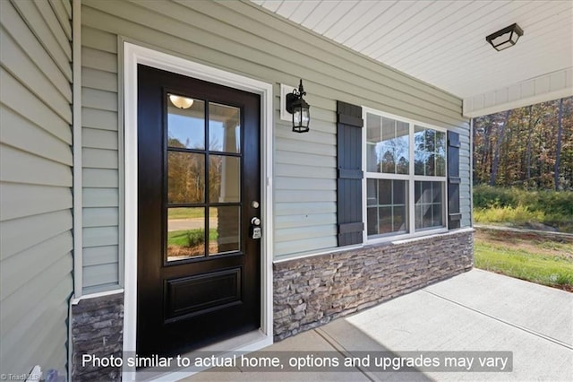 view of exterior entry with stone siding and a porch