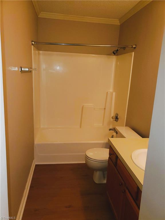 full bathroom featuring crown molding, hardwood / wood-style flooring,  shower combination, vanity, and toilet