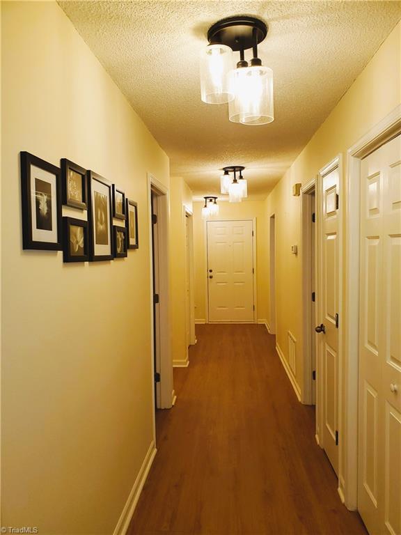 corridor featuring dark hardwood / wood-style flooring and a textured ceiling