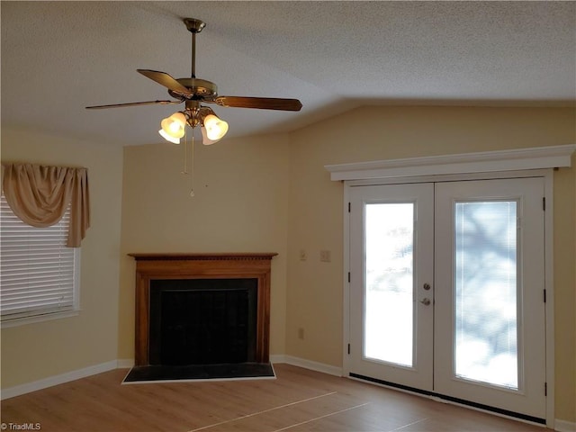 unfurnished living room with french doors, ceiling fan, lofted ceiling, and a textured ceiling