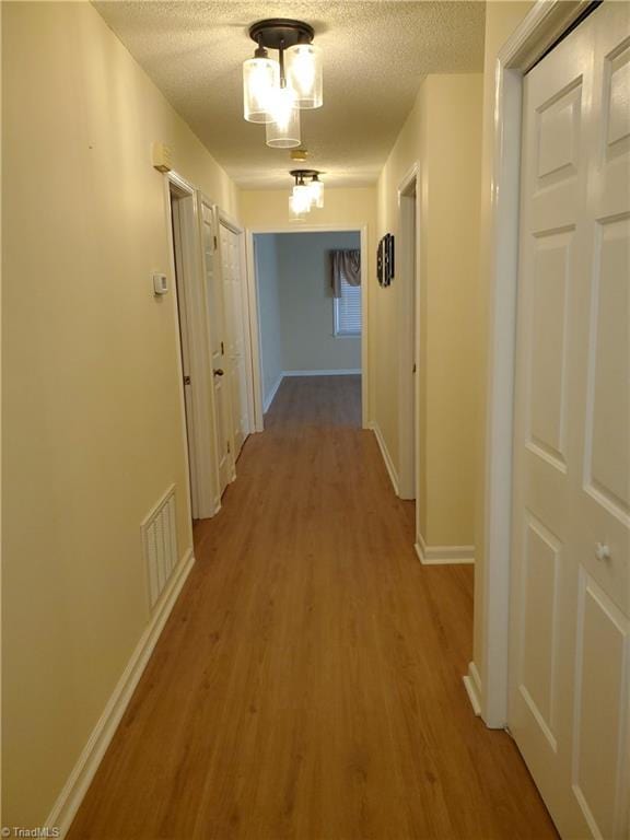 hallway featuring light hardwood / wood-style floors and a textured ceiling