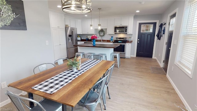 dining room featuring sink, a notable chandelier, light wood-type flooring, and a wealth of natural light