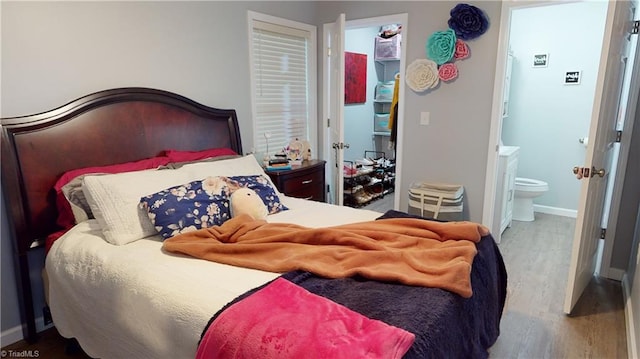 bedroom with connected bathroom and hardwood / wood-style floors