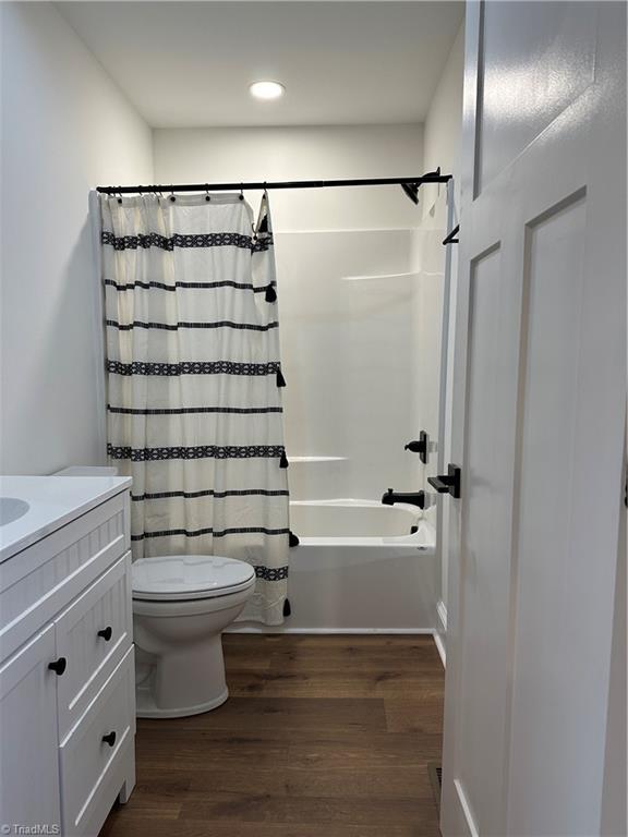 bathroom featuring recessed lighting, toilet, shower / bath combo, vanity, and wood finished floors