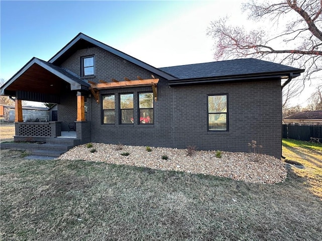 view of front of property with a front yard, brick siding, and fence