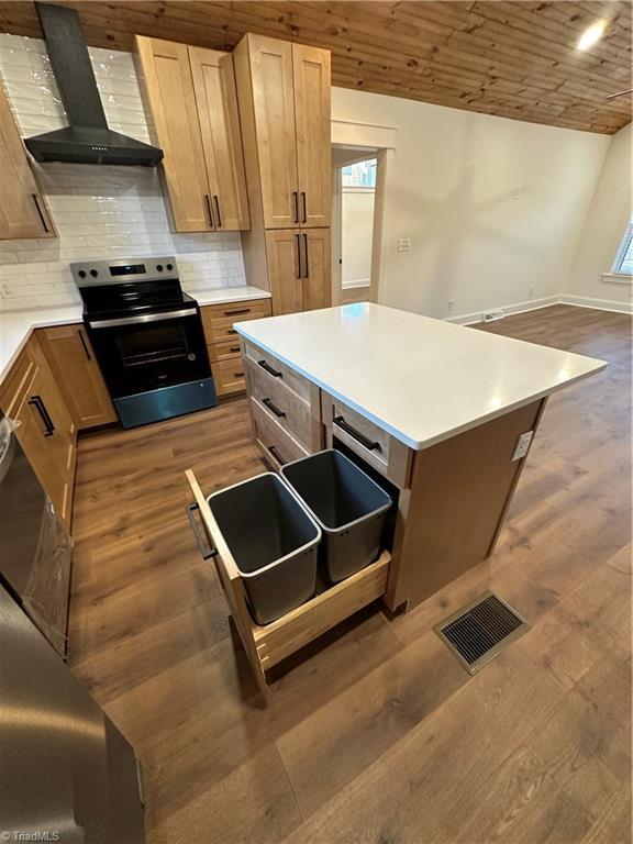 kitchen with visible vents, stainless steel range with electric cooktop, wall chimney range hood, backsplash, and dark wood-style floors