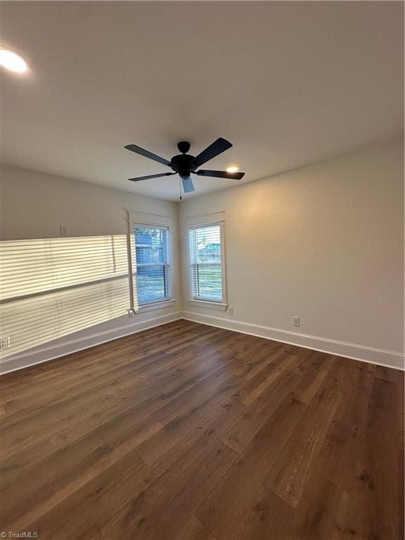 spare room with dark wood-style floors, baseboards, and a ceiling fan